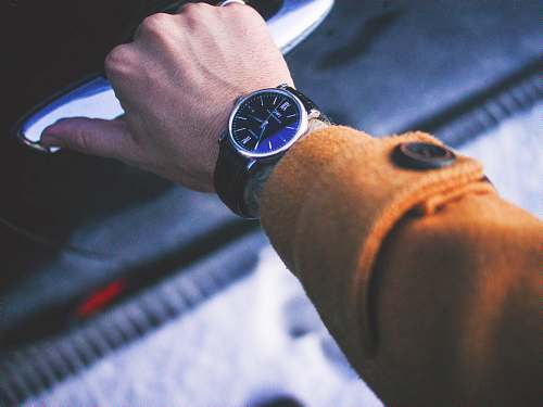 person person holding car door lever wearing round silver-colored watch watch