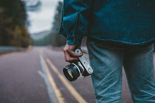 person person holding gray and black camera while standing on road camera