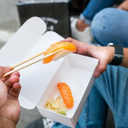 person person holding sushi with chopsticks apparel