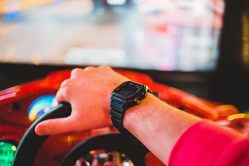 wristwatch person playing arcade driving game person