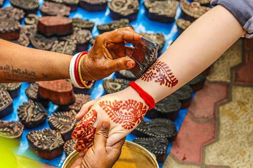 person person putting menhdi tattoo on woman's arms tattoo