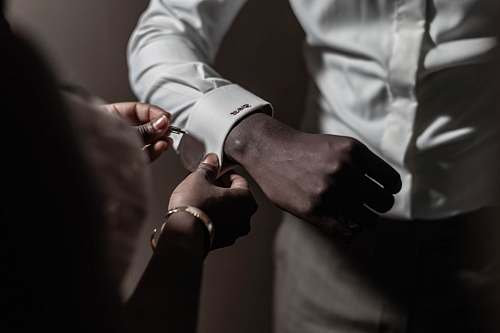 person person putting pin on another person's white dress shirt finger