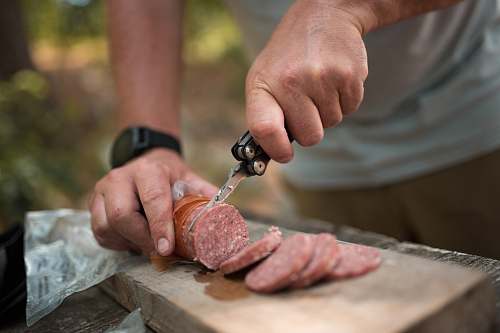 person person slicing sausage using butterfly knife finger