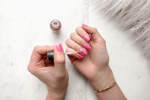 nail person spreading glittered nail polish on pink nails beauty