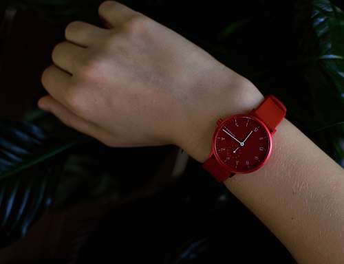 person person wearing round red analog watch wristwatch