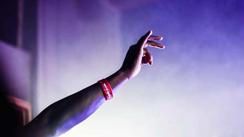 person person with red silicone band raising right hand arm