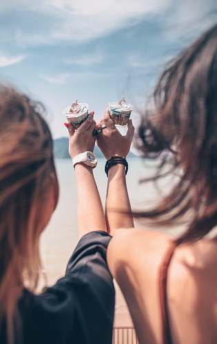 person shallow focus photo of person holding cupcakes finger