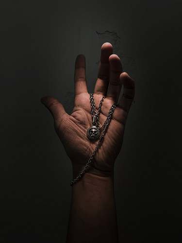 person silver-colored pendant necklace finger
