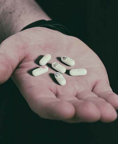 person six white medication pills on hand people