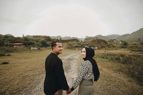 apparel smiling woman and man holding hands while walking clothing