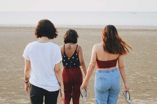 person three women walking towards shoreline apparel