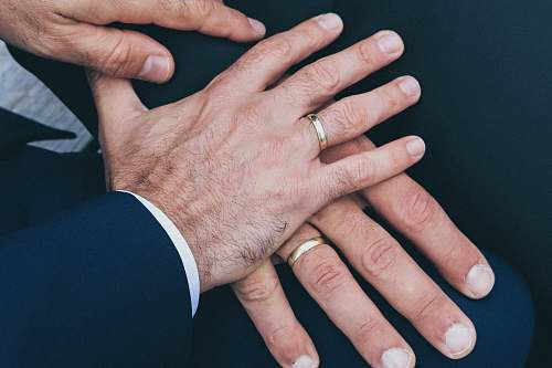 person two man's hands wearing gold-colored wedding rings people