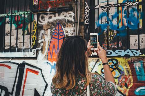 graffiti woman holding phone taking picture at wall phone