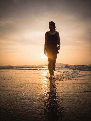 person woman standing on shore during golden hour standing