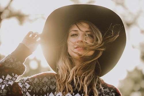 person woman touching her hat during daytime in shallow focus photography people