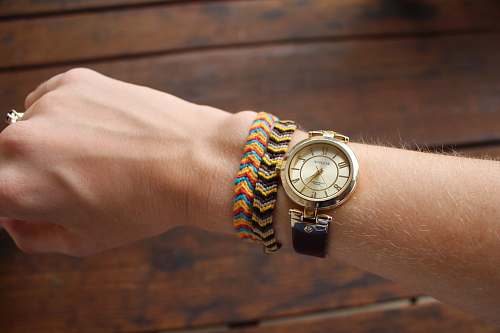 bangles person wearing gold-colored analog watch with black strap ornament