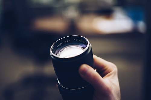 hand person holding black camera lens holding