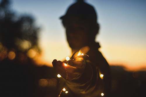 bright person holding string lights at nightitme twilight