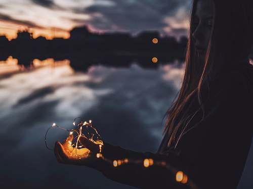 hand woman holding string lights at dusk fairy lights