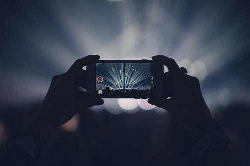 iphone person taking video of live concert cell phone