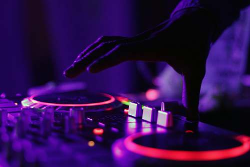 purple selective focus silhouette photography of man playing red-lighted DJ terminal dj