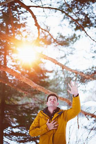 prayer man raising left hand, right hand on chest closed eyes standing outdoor under shade of tree during daytime person