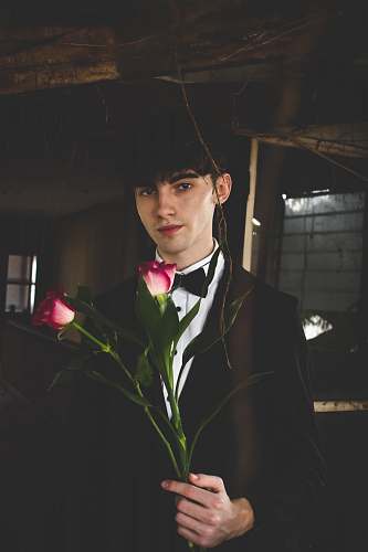person man wearing black and white formal suit holding two red roses human