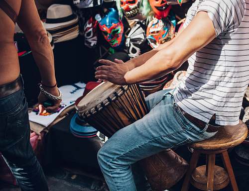 person men wearing white striped shirt playing djembe music
