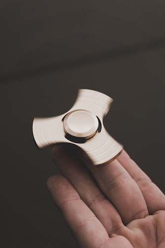 human person holding brown 3-blade fidget spinner person