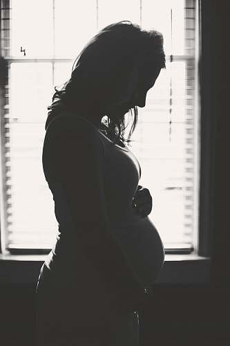 silhouette pregnant woman standing inside room during daytime pregnancy