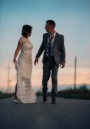 person woman in wedding dress beside man in gray suit jacket human