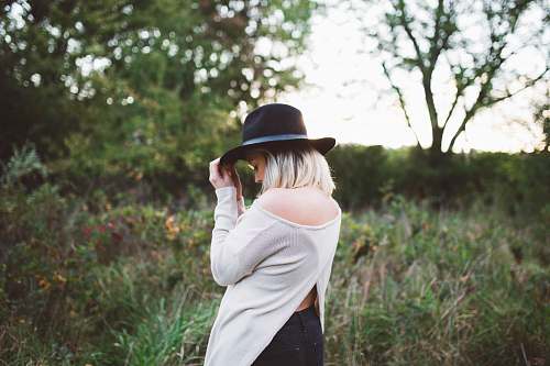 person woman in white off shoulder long sleeved top holding black hat girl