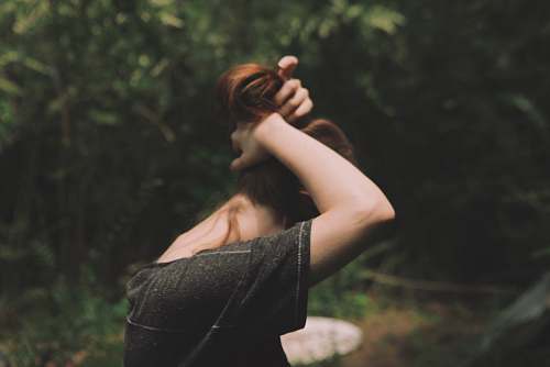human woman wearing black shirt tying up hair girl