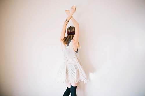 human woman wearing white sleeveless top with hands above head dance