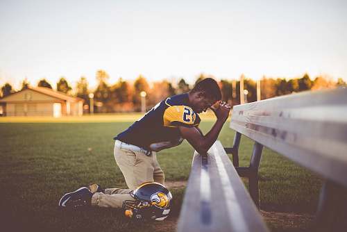 people baseball player kneeling on ground bench