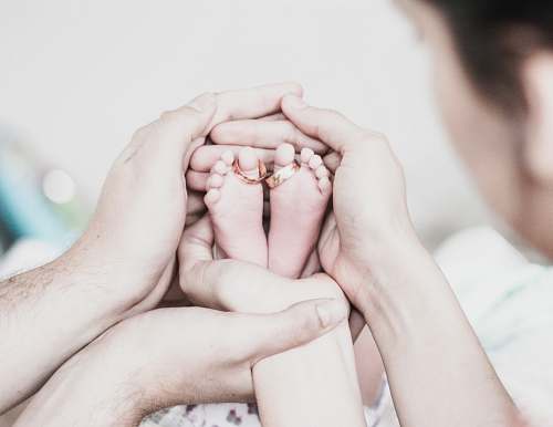 human couple holding baby's feet finger