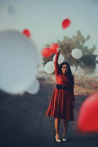 people focus photography of woman standing on road raising her left hand red