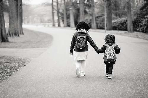 black-and-white grayscale photography of two toddlers walking on road walking