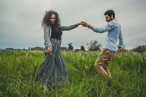 human man and woman holding hands on green field nature