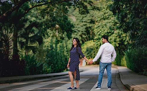 human man and woman standing near road while holding hands during daytime apparel