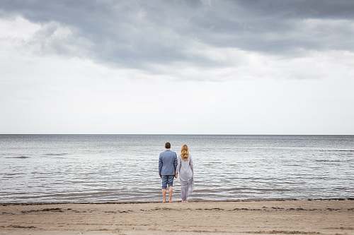 human man and woman standing on shore sea