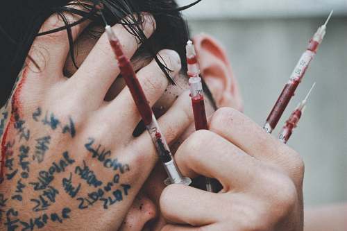 human man holding syringes of red stain people