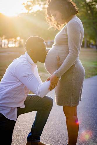 clothing man kneeling in front of pregnant woman apparel