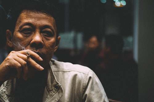 human man smoking cigarette during nighttime people