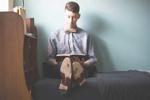 reading man wearing gray dress shirt reading book shoe