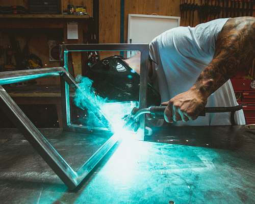 people man welding two rectangular gray metal frames human