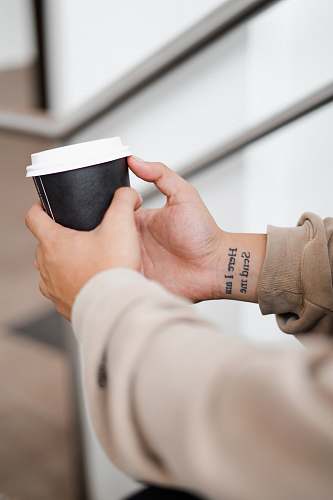 human person holding black and white coffee cup cup
