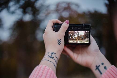 human person holding black camera selective focus photography skin