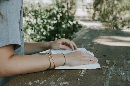 human person holding book white sitting in front of desk bible