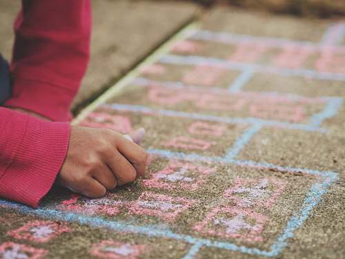 kid person holding chalk lying on concrete surface sidewalk